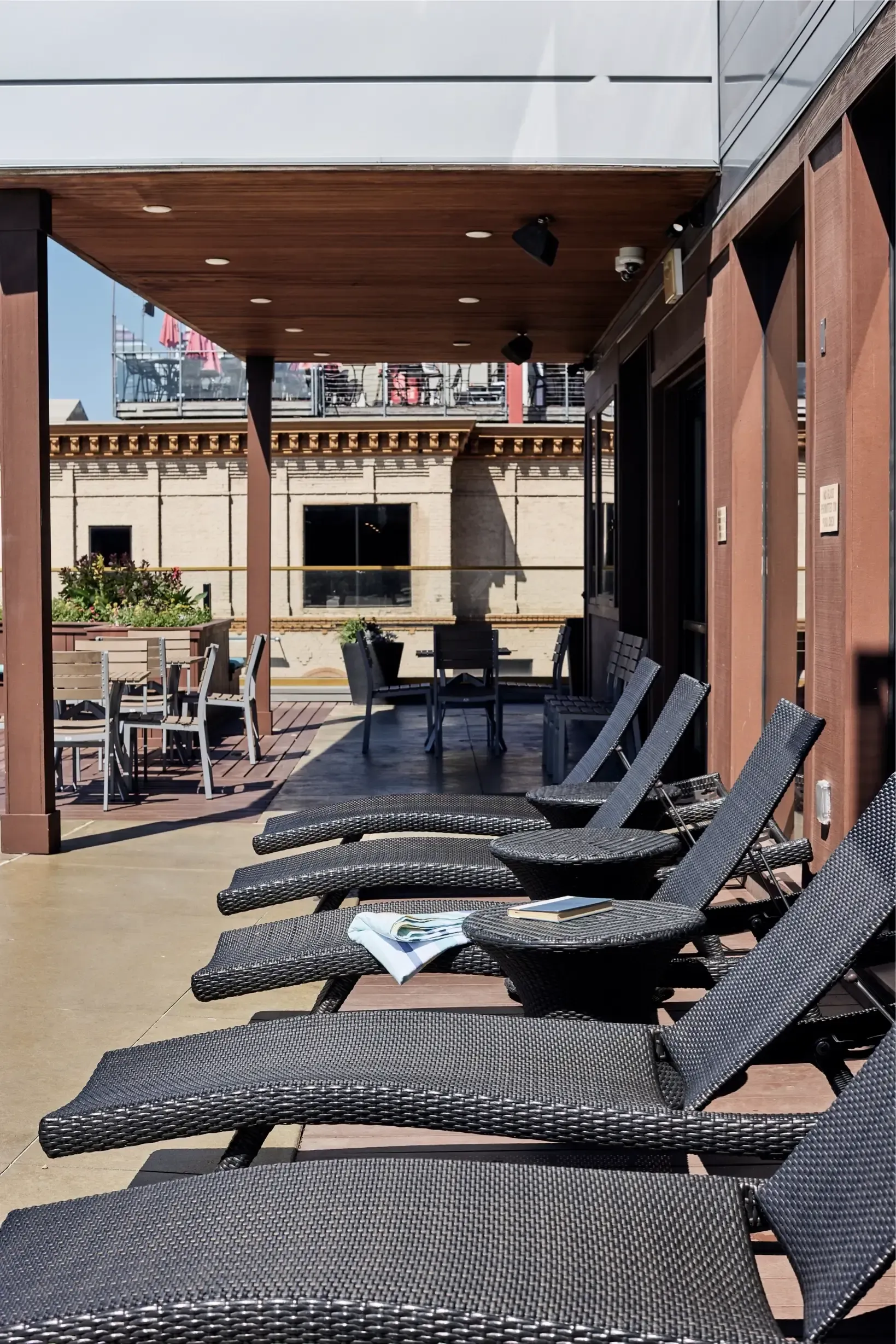 Outdoor amenity deck with wicker lounge chairs and tables under a wood-paneled ceiling at The Walkway, which offers pet-friendly apartments in Minneapolis, MN.