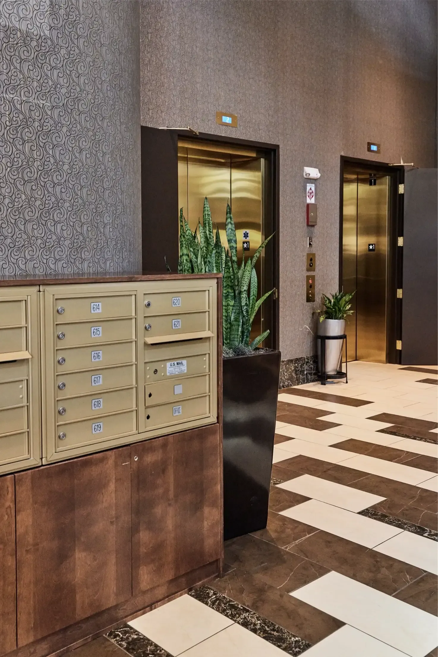 Lobby with beige mailboxes, two elevators, and potted plants at The Walkway, which offers Minneapolis apartments for rent.