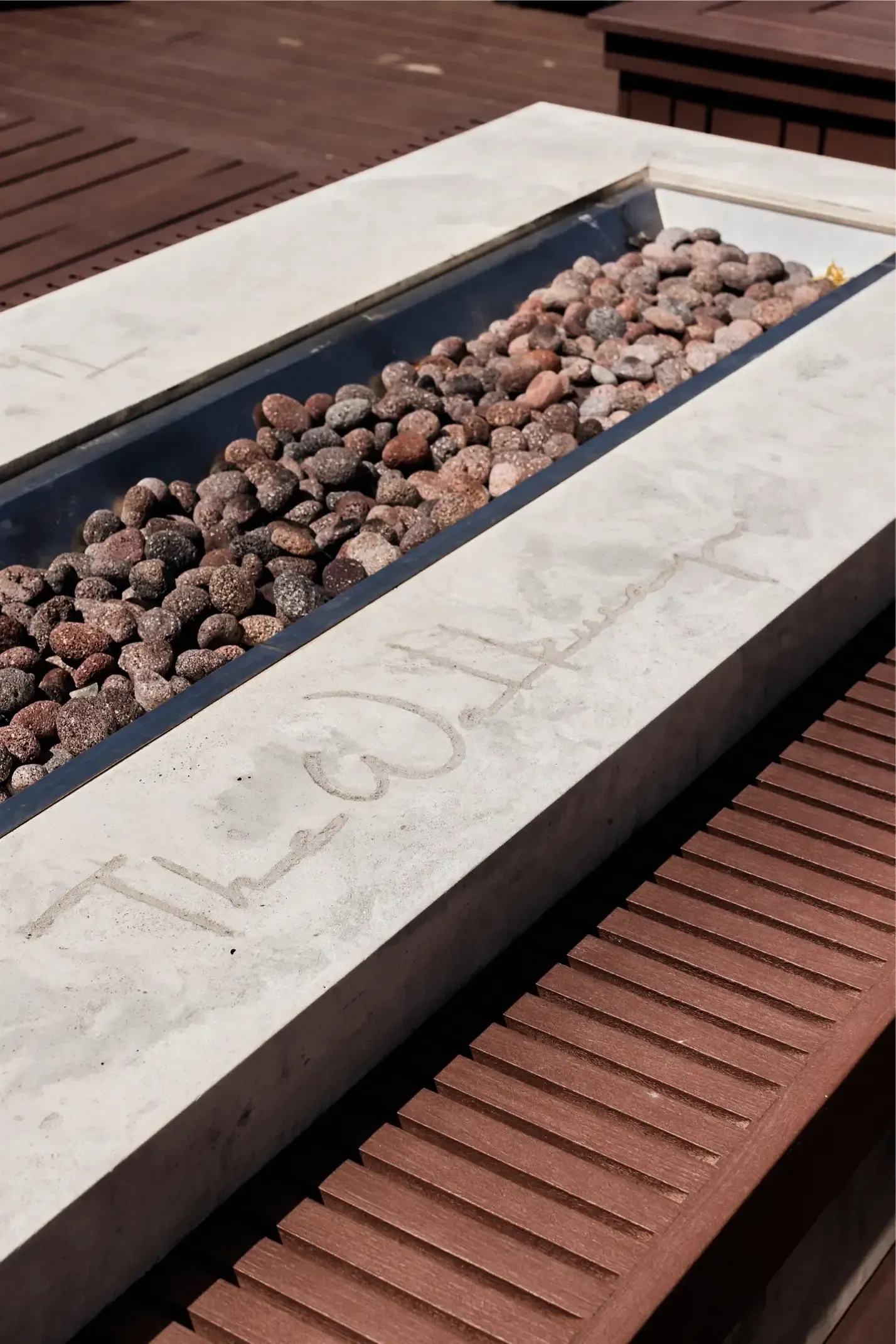Concrete planter filled with brown pebbles on a wooden deck at The Walkway, which offers apartments in Minneapolis, MN.
