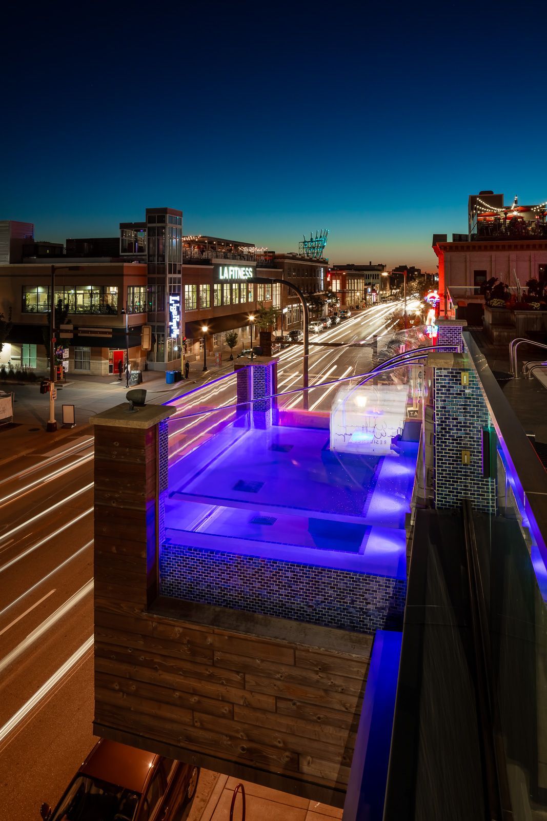 Rooftop pool with blue lighting overlooking a city street at dusk at The Walkway, which offers pet-friendly apartments in Minneapolis, MN.