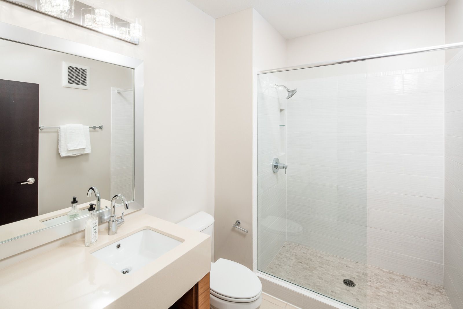 Modern apartment bathroom with sink, toilet, and glass-enclosed shower at The Walkway, which offers Uptown apartments in Minneapolis, MN.