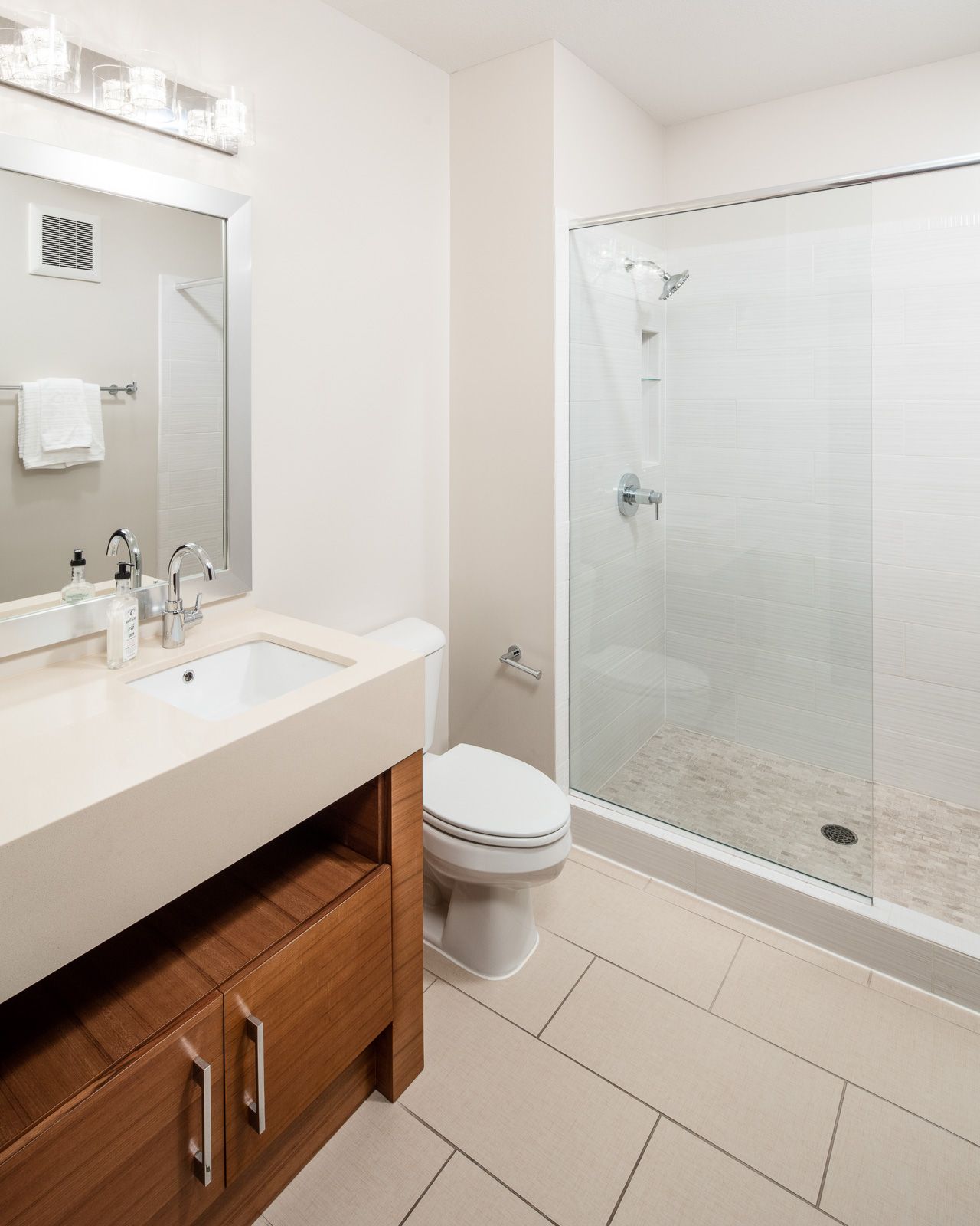 Bathroom with a vanity, sink, toilet, and glass-enclosed shower at The Walkway, which offers Uptown apartments in Minneapolis, MN.