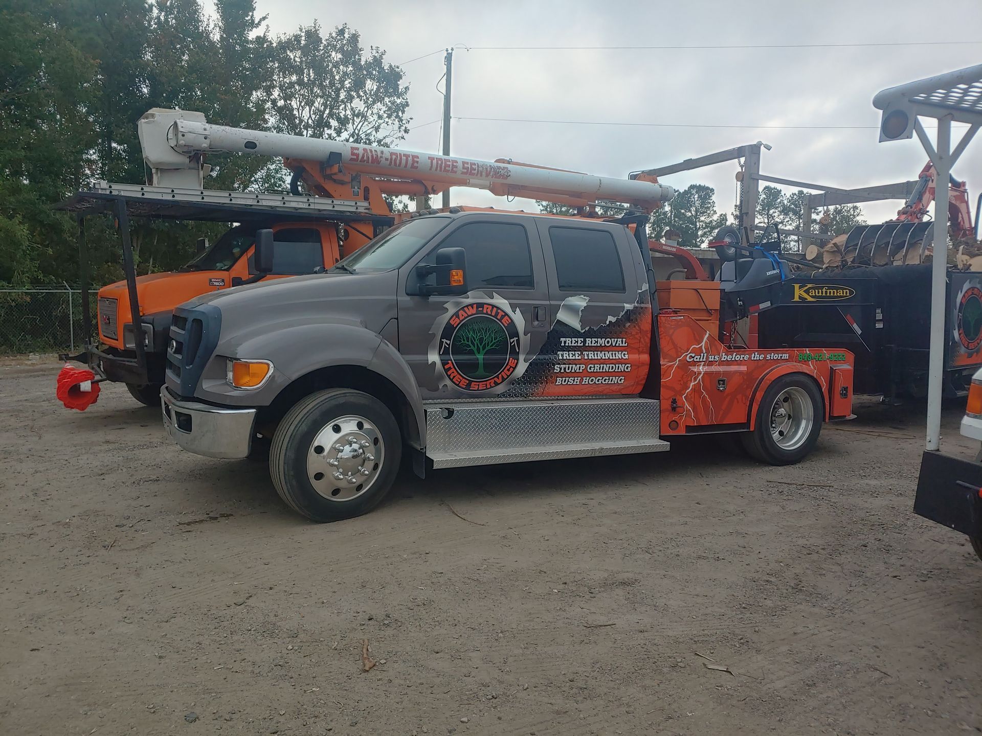 A truck with a crane on the back of it is parked in a dirt lot.