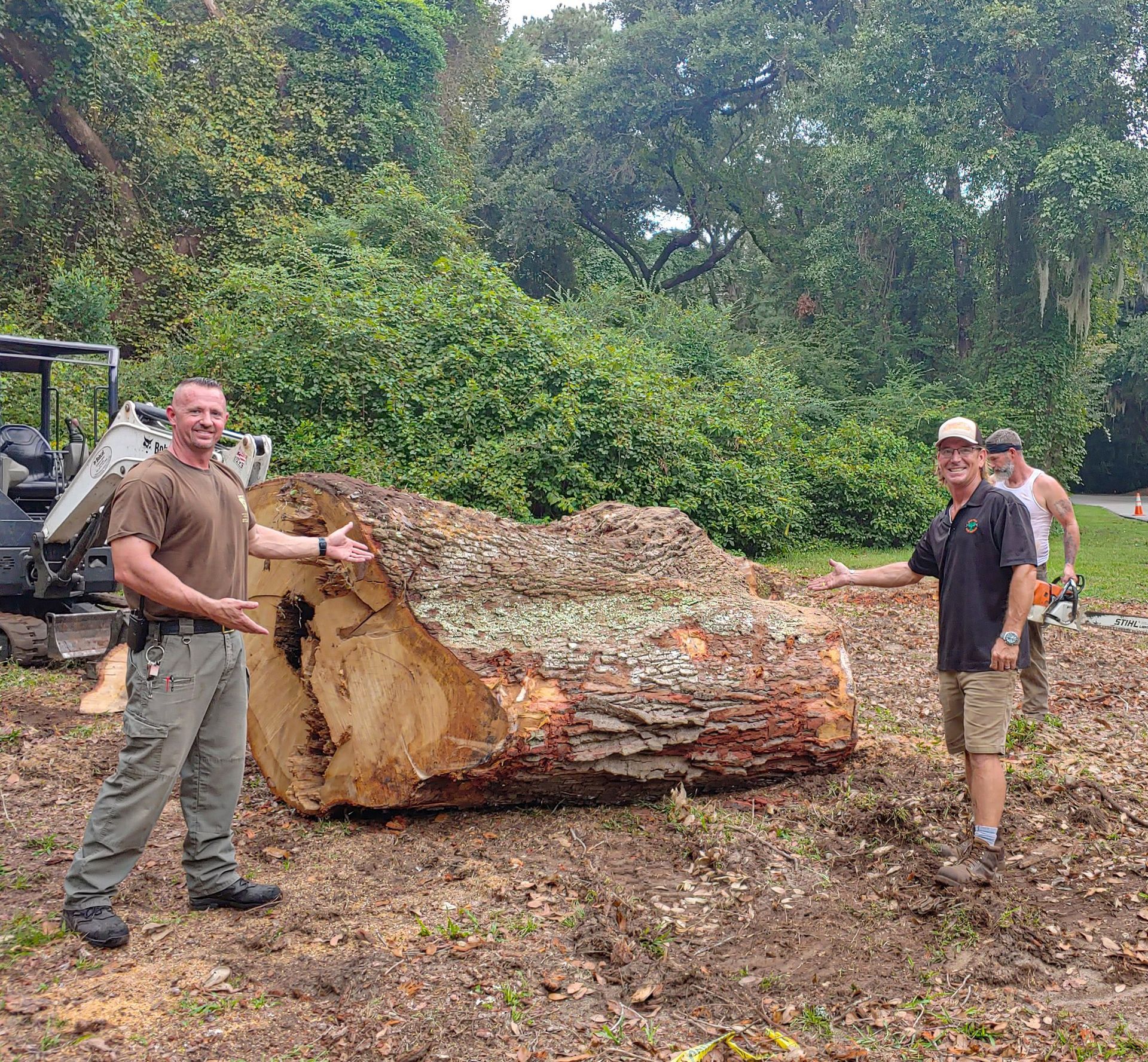 A group of men are standing next to a large log in a field.