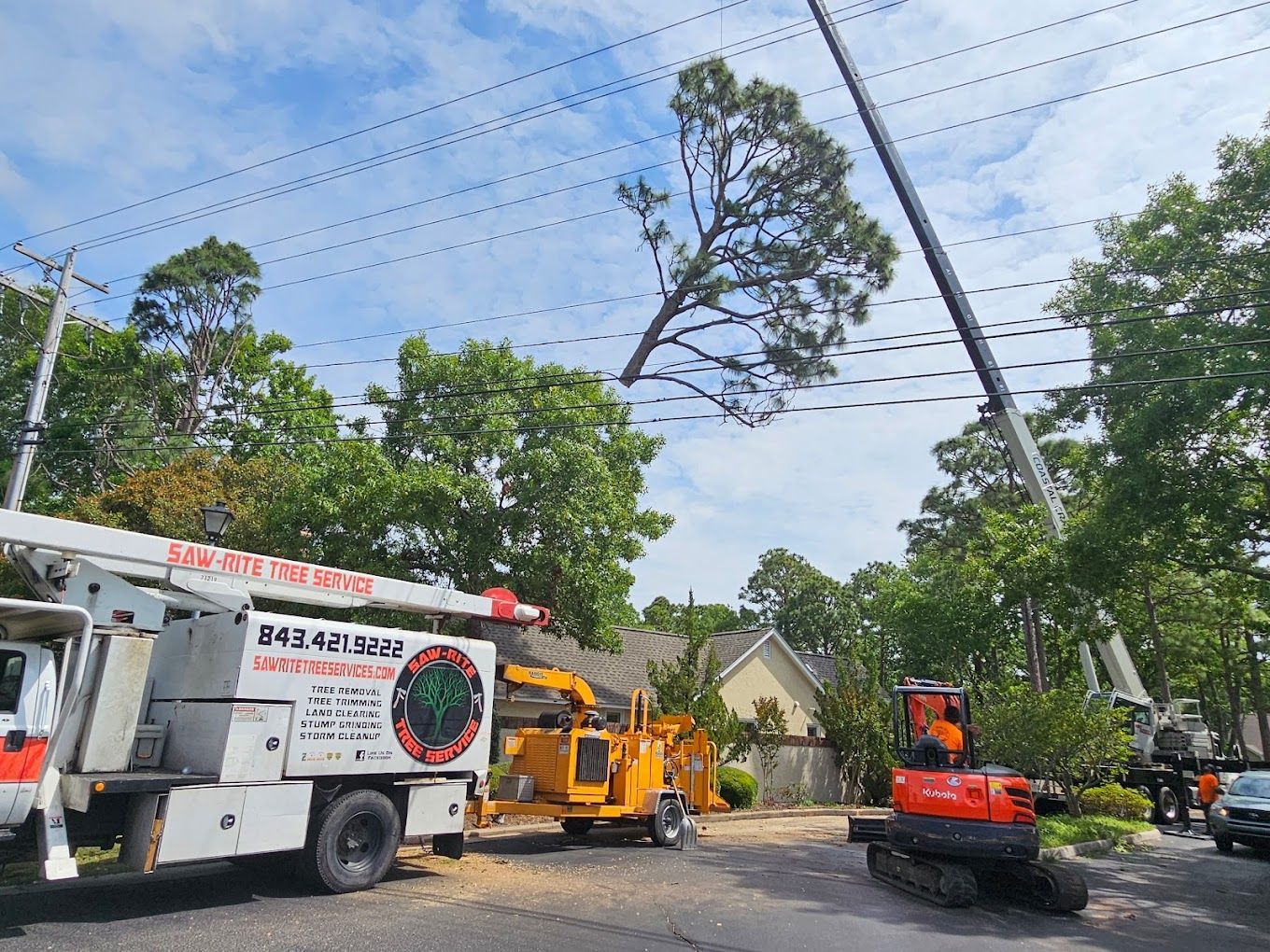 A tree cutting truck is parked on the side of the road next to a house.