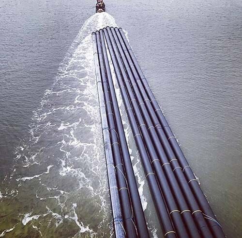 Un barco lleva un montón de tubos en el agua.