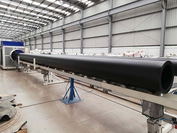 Un tubo negro de gran tamaño se encuentra sobre una cinta transportadora en un almacén.