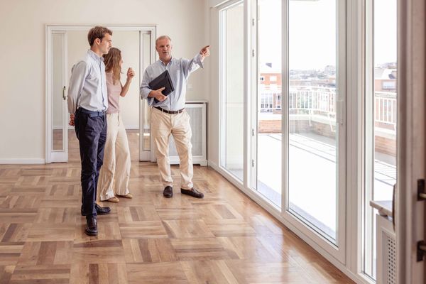 Un agent immobilier désigne la vue du doigt tandis qu'un couple visite un nouvel appartement.