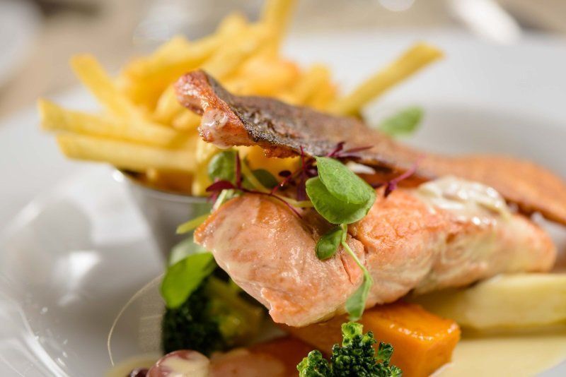 A close up of a plate of food with french fries on a table.