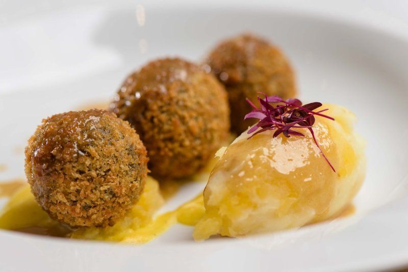 A plate of food with meatballs and mashed potatoes on a table.