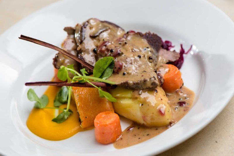 A white plate topped with meat , carrots and mashed potatoes.