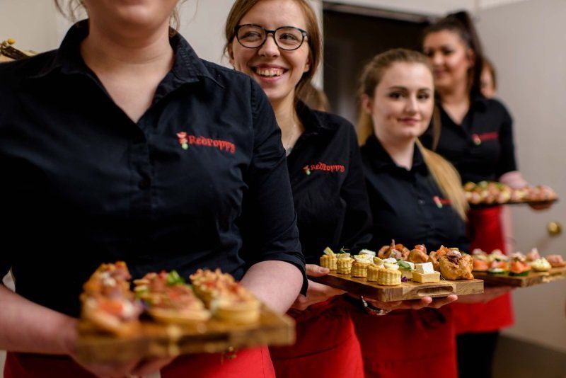 A group of women are holding trays of food in their hands.
