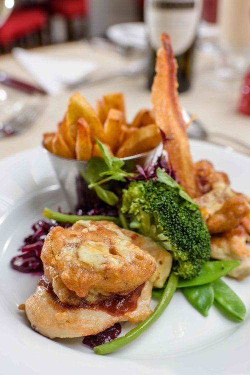 A plate of food with french fries and broccoli on a table.