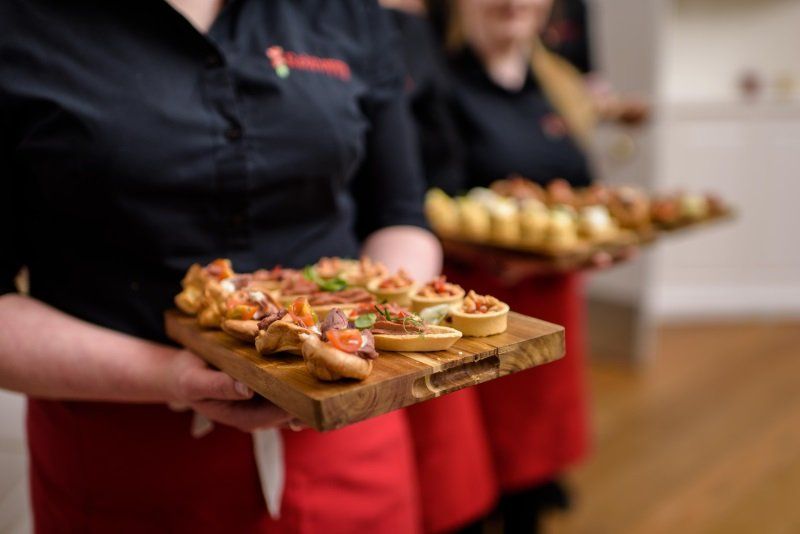 Two women are holding trays of food in their hands.