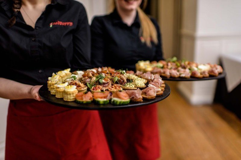 Two women are holding trays of food in their hands.