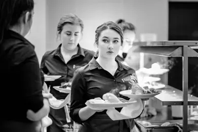 A woman is holding a plate of food in a black and white photo.