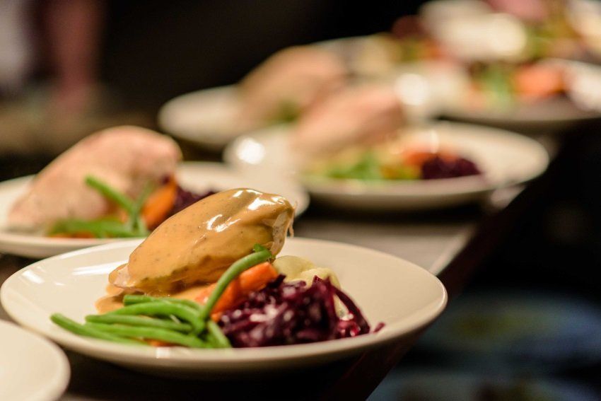 A row of plates of food are lined up on a table.
