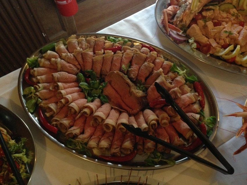 A plate of meat and vegetables with tongs on a table