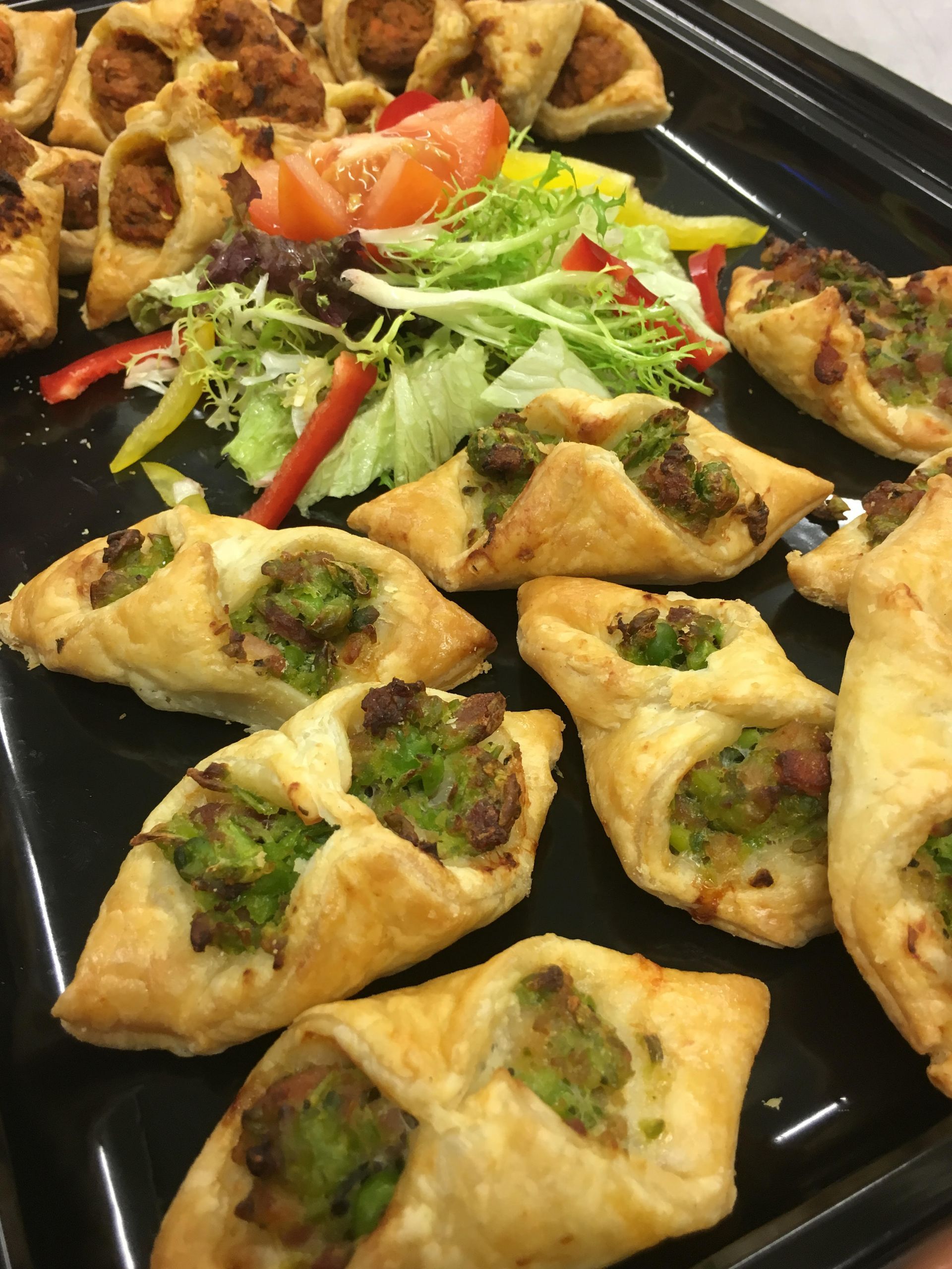 A tray of food with a salad in the background