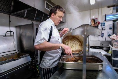 A man is cooking food in a kitchen.