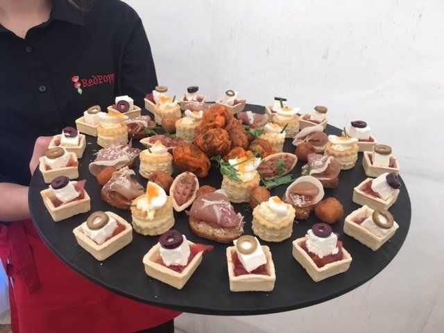 A woman is holding a tray of appetizers on a table.