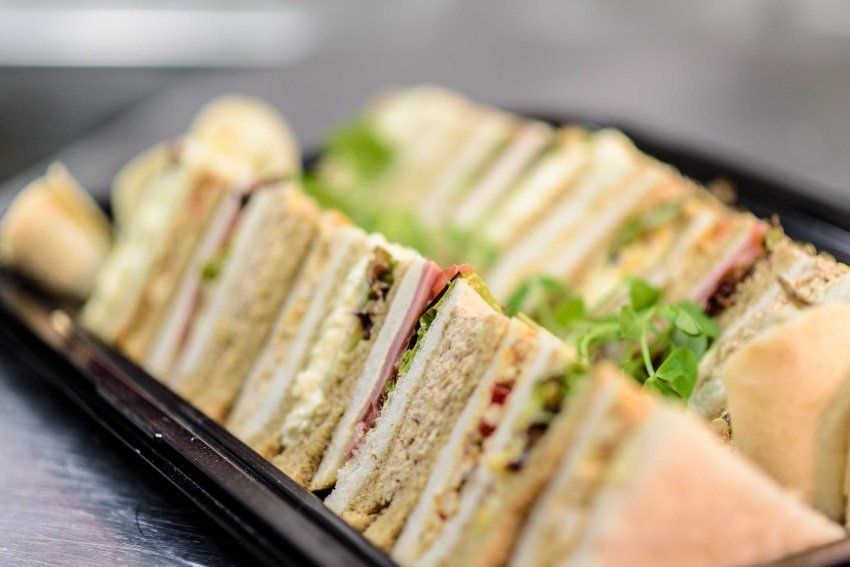 A close up of a tray of sandwiches on a table.