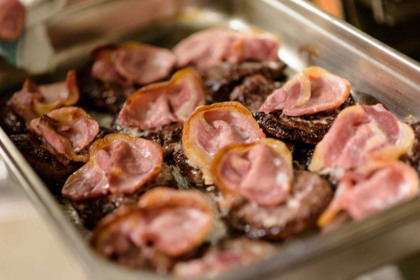 A close up of a pan filled with meat and bacon.