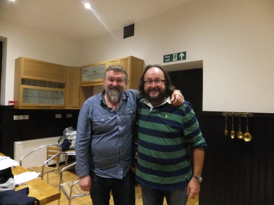 Two men are posing for a picture in a kitchen