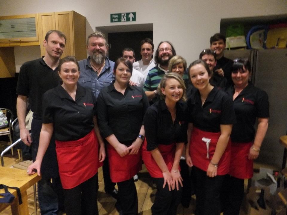 A group of people posing for a picture in front of a green exit sign