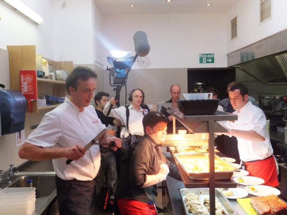 A group of people in a kitchen with a green exit sign