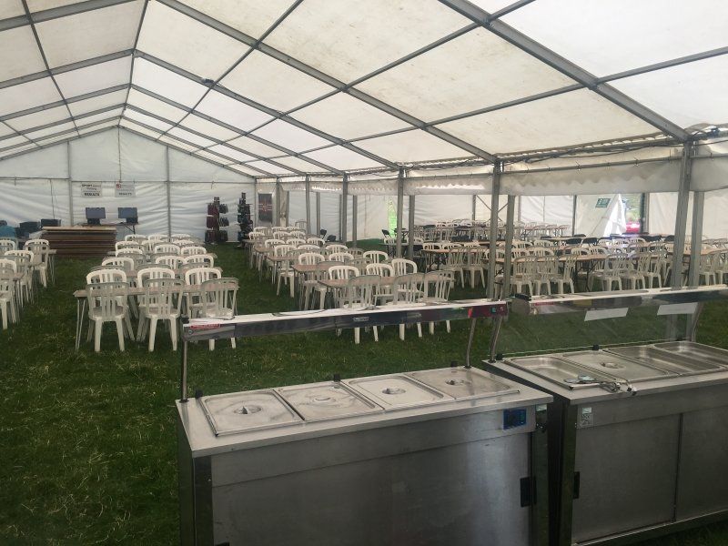 A large tent with tables and chairs inside of it.