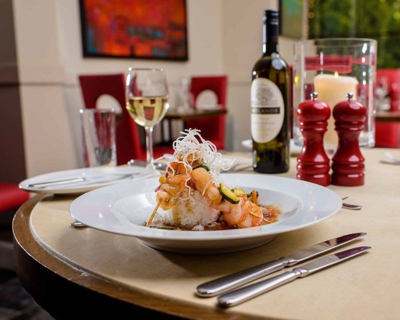 A plate of food is sitting on a table next to a bottle of wine.