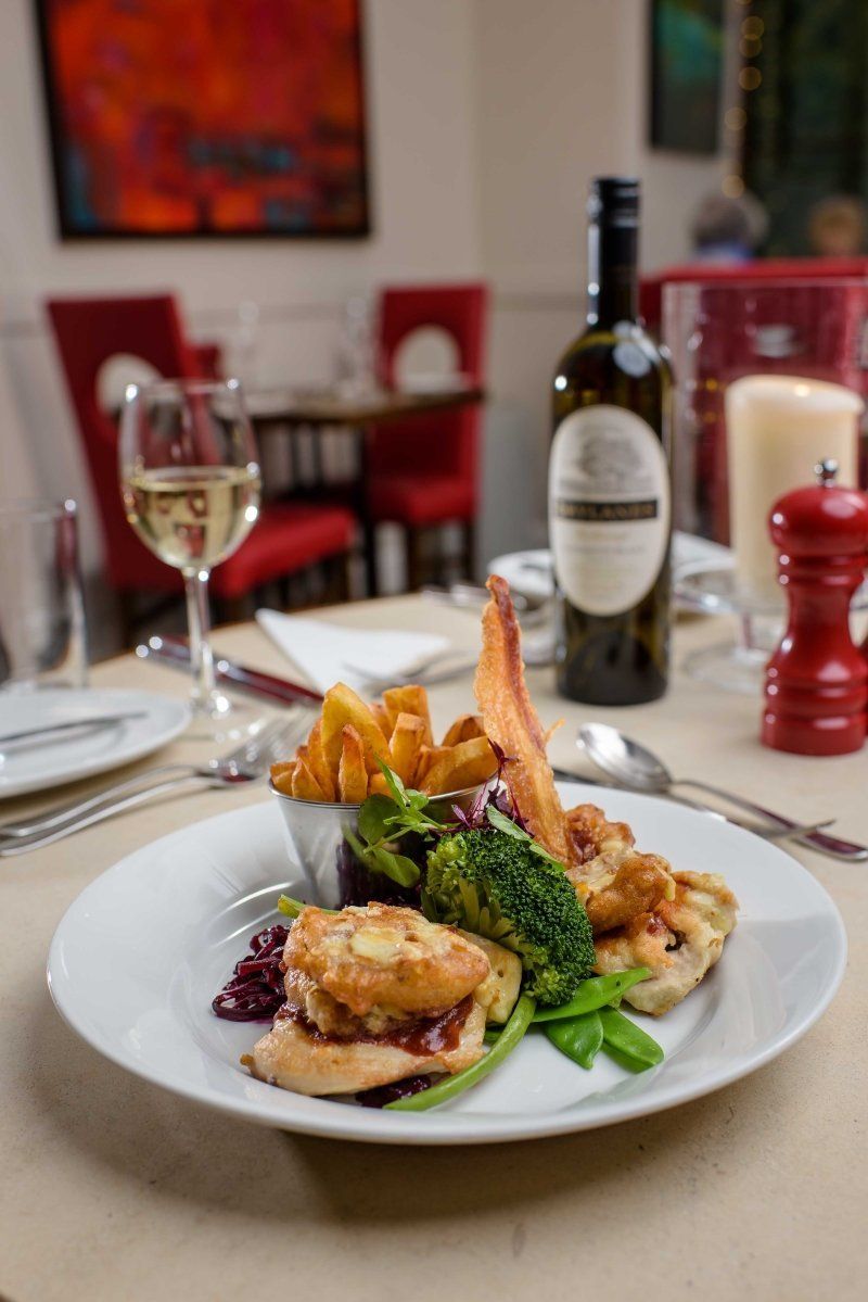 A plate of food with a bottle of wine in the background