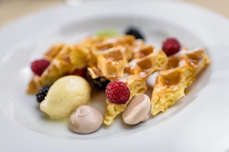 A white plate topped with waffles , ice cream and berries.