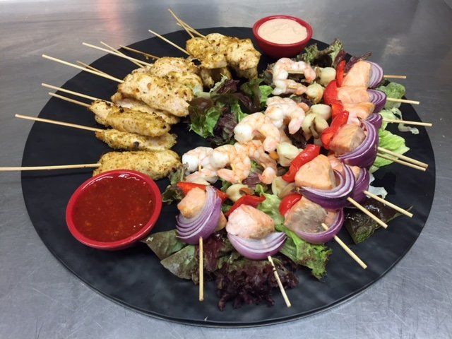 A plate of food with shrimp and chicken on skewers