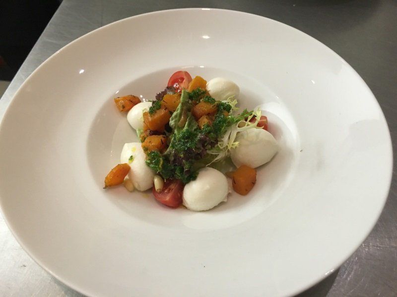 A white plate topped with a salad of tomatoes and mozzarella