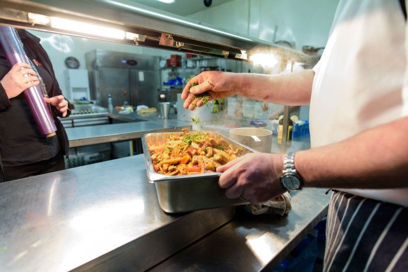 A man is holding a tray of food in a kitchen.