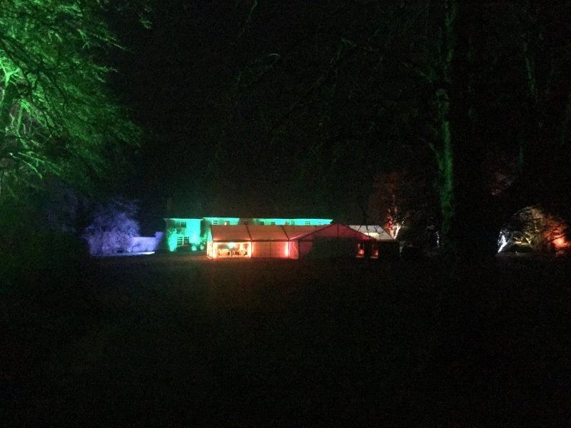 A house is lit up with green , red , and blue lights at night.