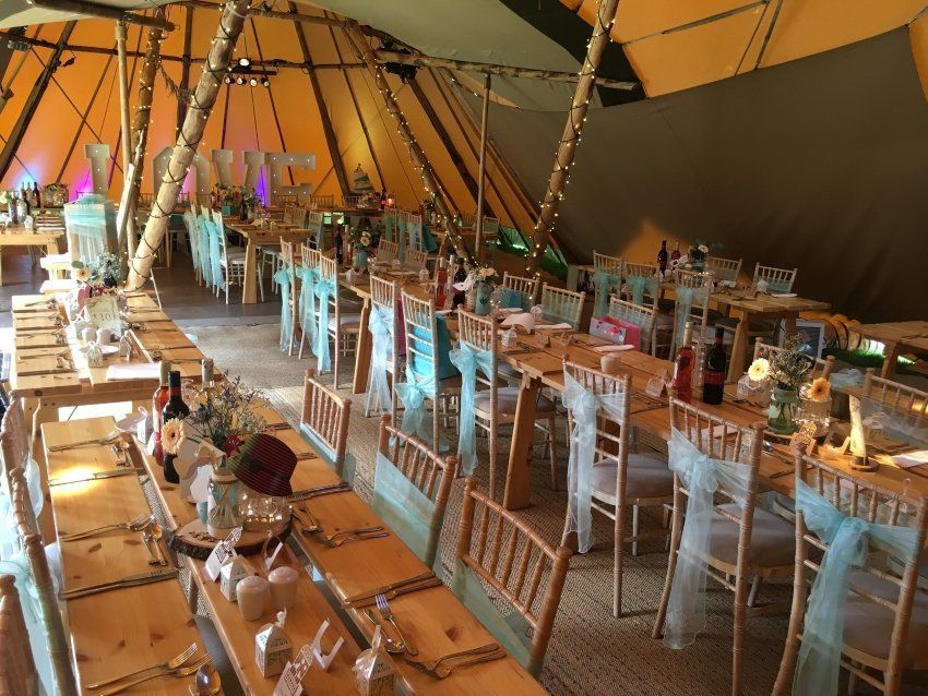 A large tent with tables and chairs set up for a wedding reception
