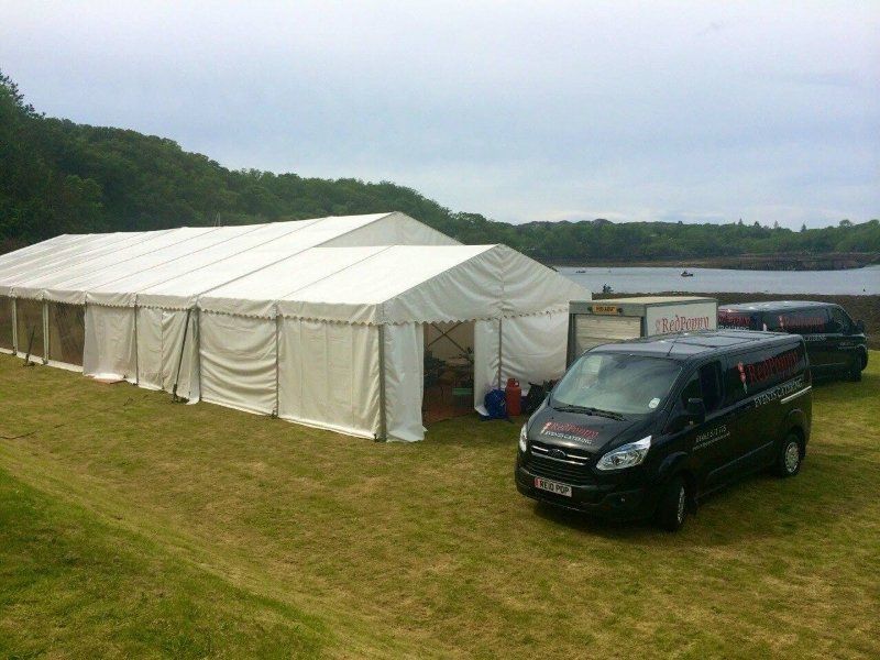 A black van is parked in front of a large white tent