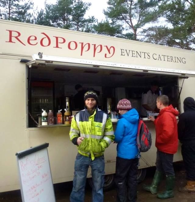 A group of people standing in front of a red poppy event catering trailer