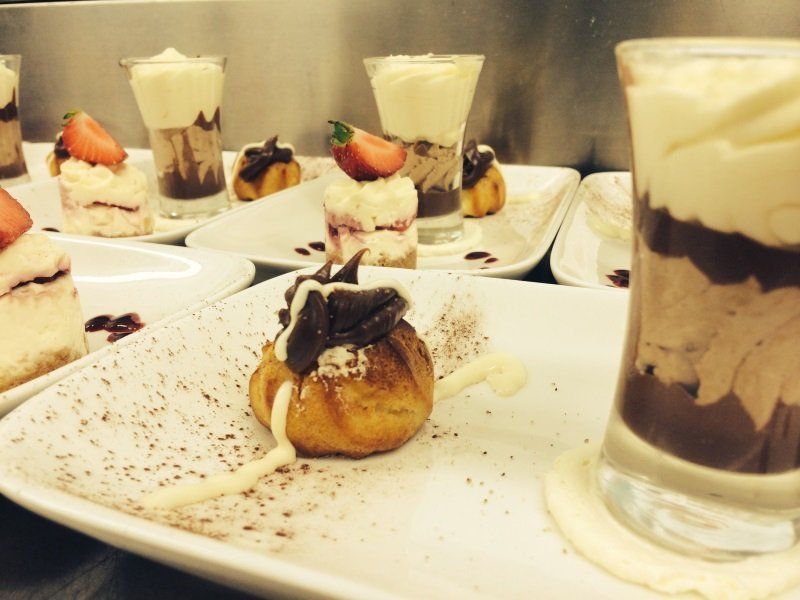 A white plate topped with desserts and a shot glass
