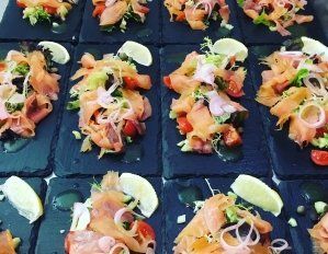 A tray of food with smoked salmon and vegetables on a table.