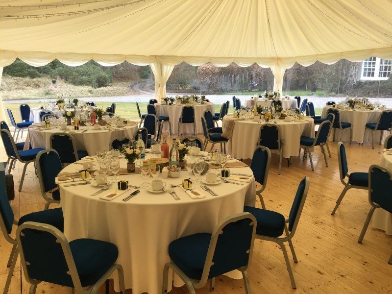 A large tent with tables and chairs set up for a wedding reception