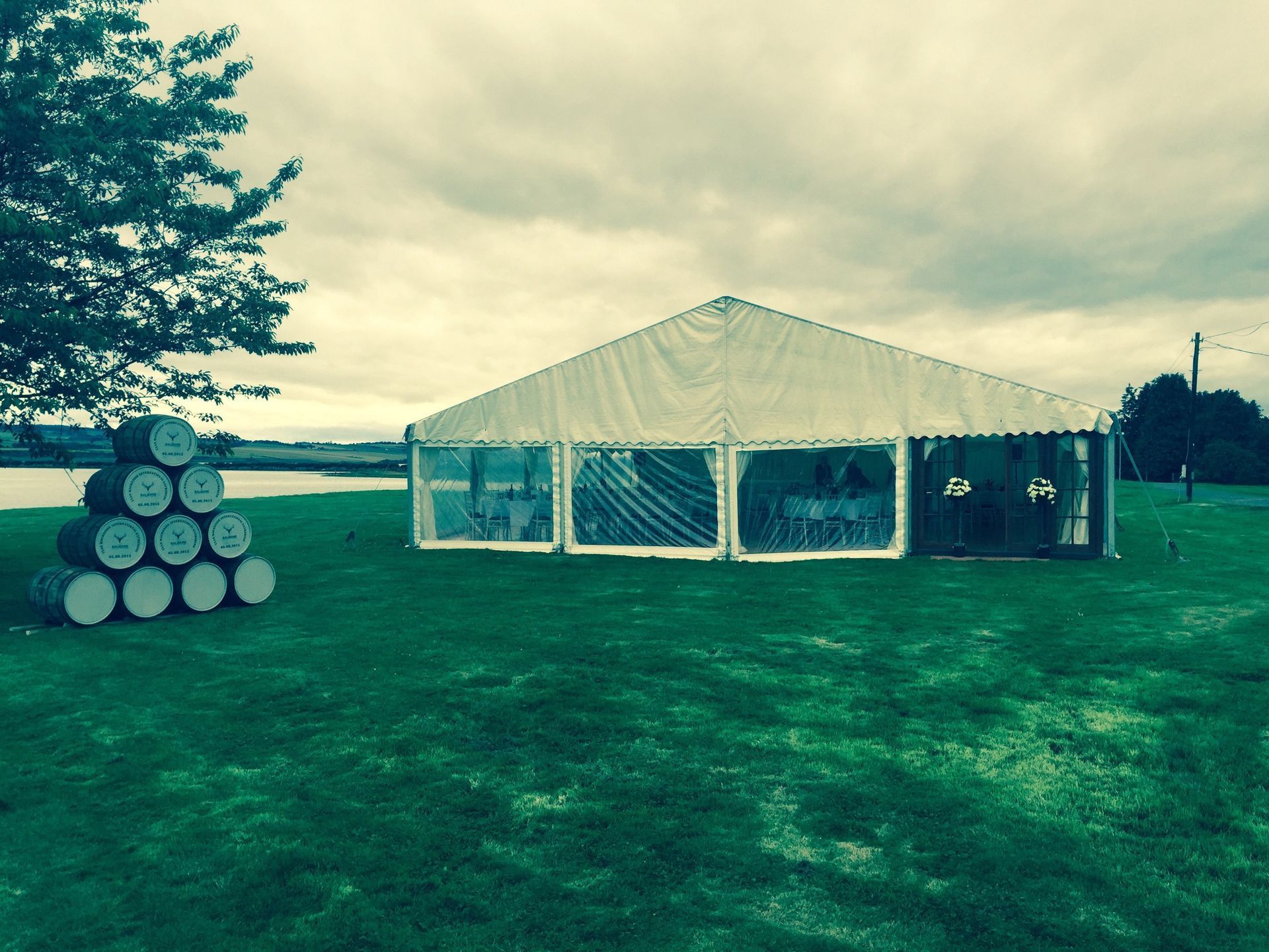 A large white tent is sitting in the middle of a grassy field.