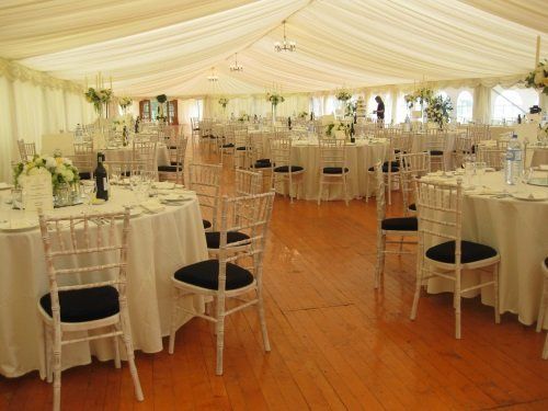 A large tent with tables and chairs set up for a wedding reception.