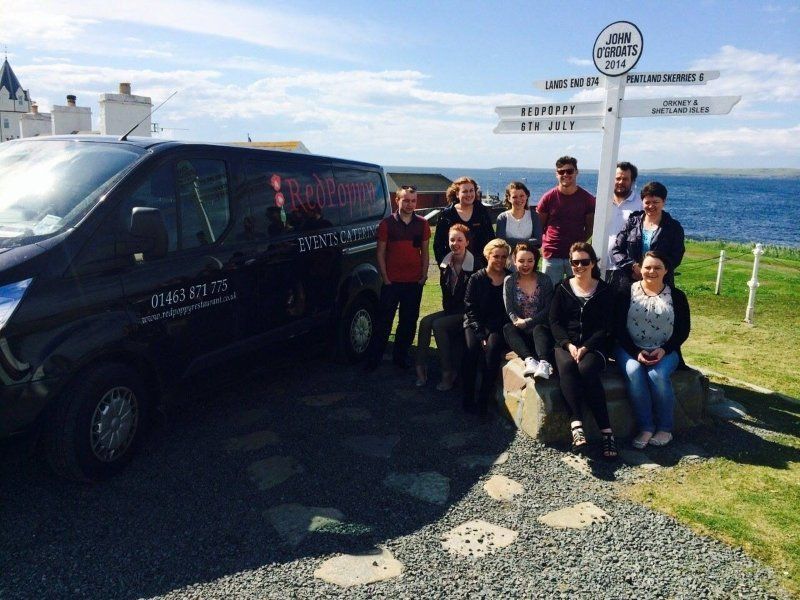 A group of people posing for a picture in front of a van