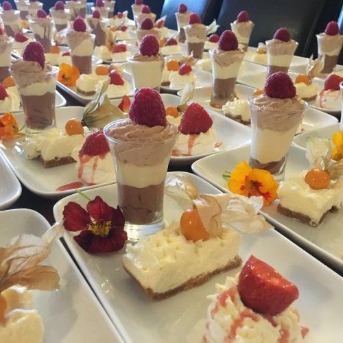 A bunch of desserts on plates with strawberries on top