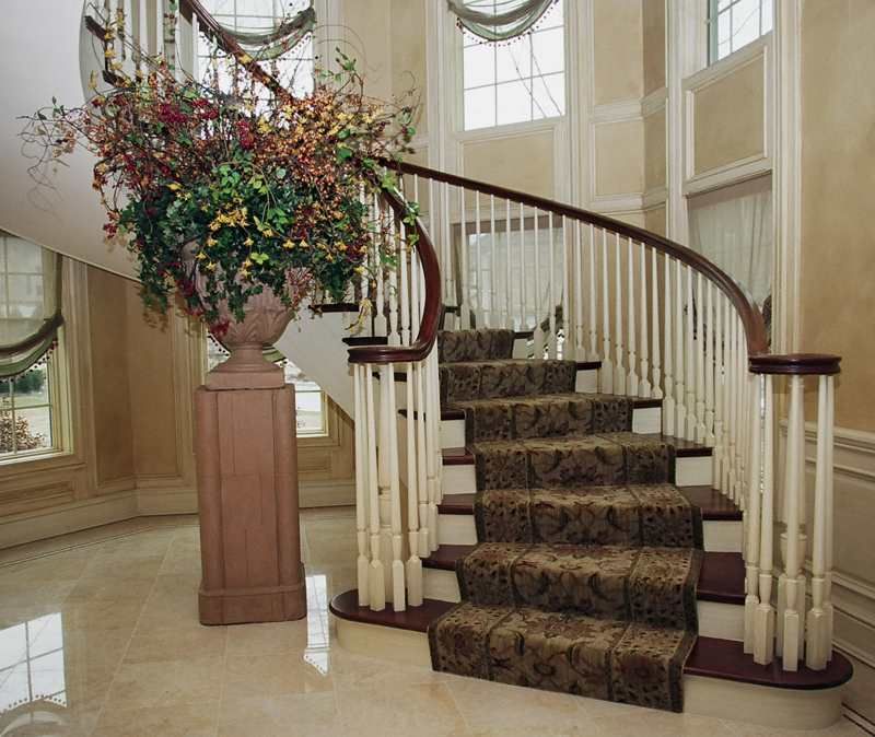 A curved staircase with a carpeted staircase and a vase of flowers