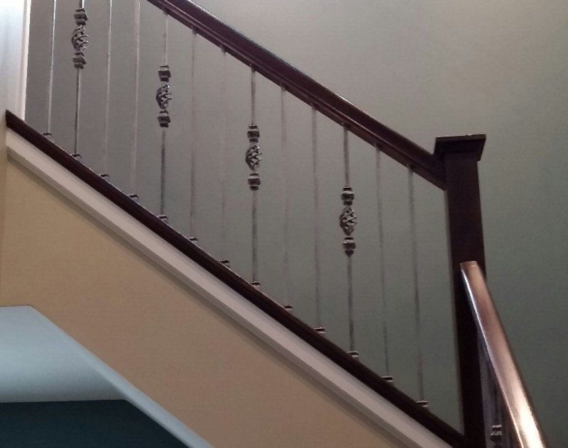 A staircase with a metal railing and a wooden handrail